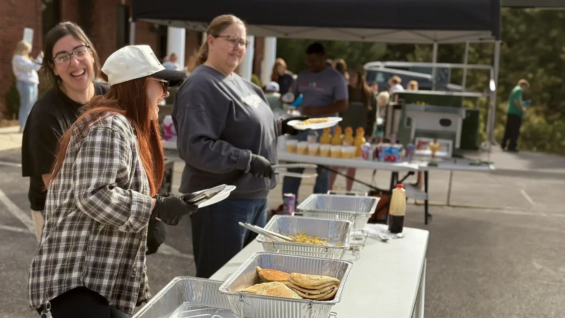 Volunteers sharing smiles while serving pancakes and breakfast at The Good Table.